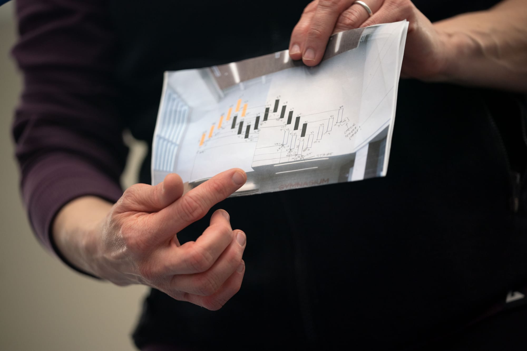 A woman's finger points on a map of the layout for an art installation.