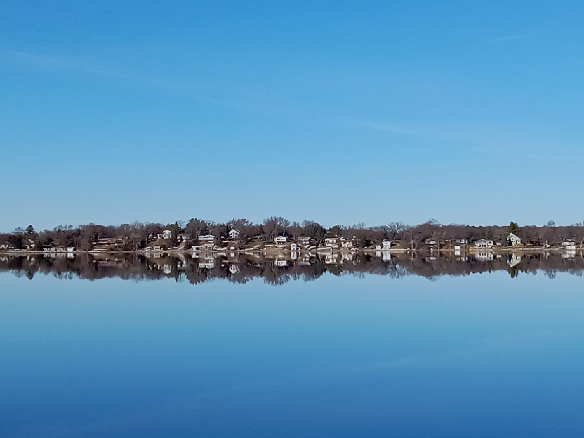 Houses are seen along the shoreline of a lake with open water in December in Minnesota. 