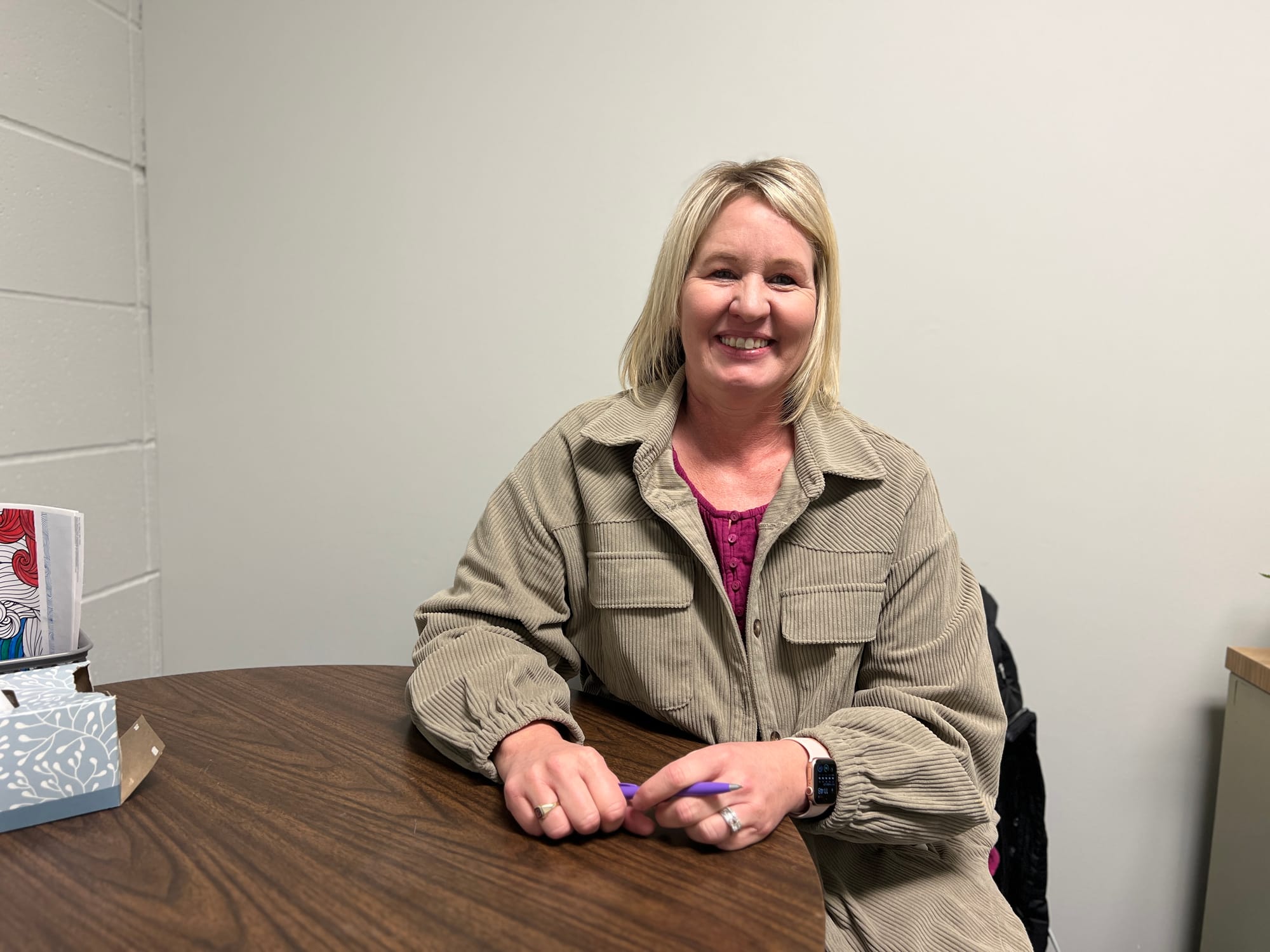 Woman sits at table in small conference room