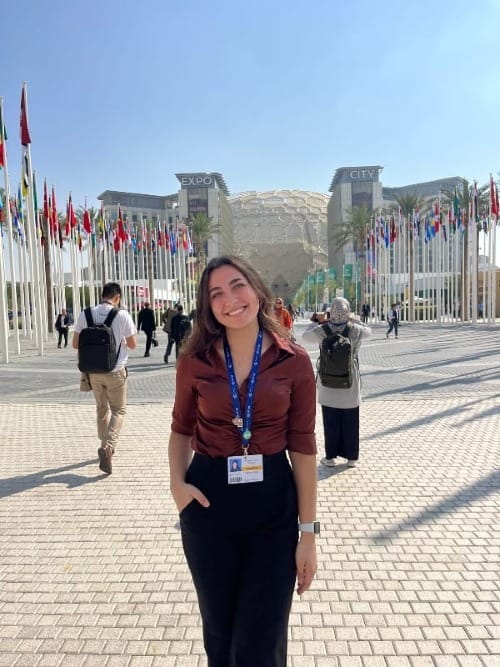 Young woman poses for a photo in front of flags