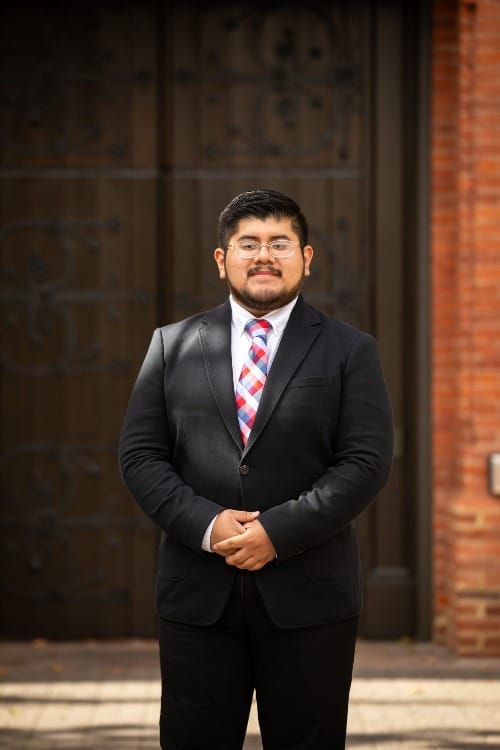 Young man in a suit and tie poses for a photo.