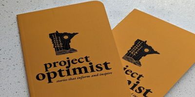 Two Project Optimist yellow notebooks