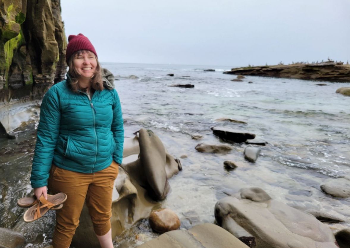 Photo of Project Optimist founder Nora Hertel smiling on a beach in La Jolla, Cali. in March 2023. 
