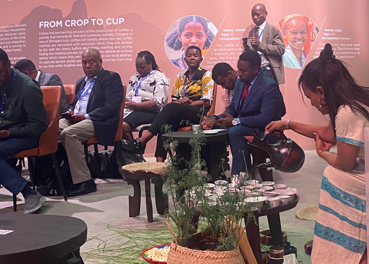 A woman performs traditional Ethiopian coffee ceremony at COP28 while people in the audience look on. 