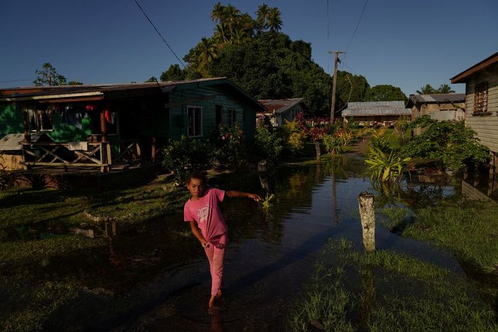 Local girl Tokasa Robanakadavu, 10, wades through seawater flooding her community during high tide in Serua Village, Fiji, Ju